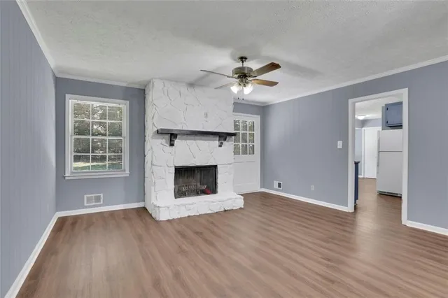 a view of a livingroom with a fireplace a ceiling fan and windows