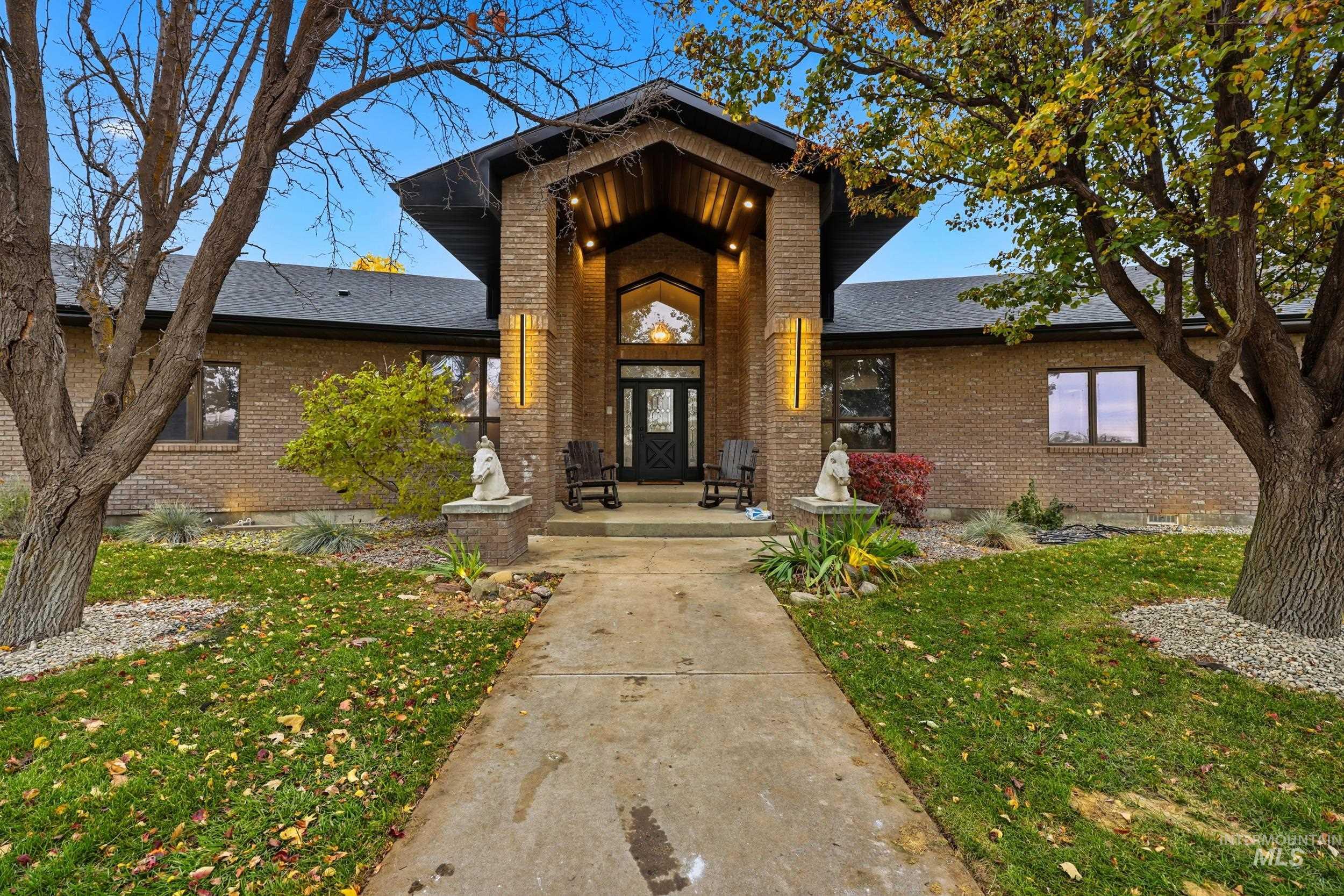 Doorway to property featuring a lawn, brick siding, and a shingled roof