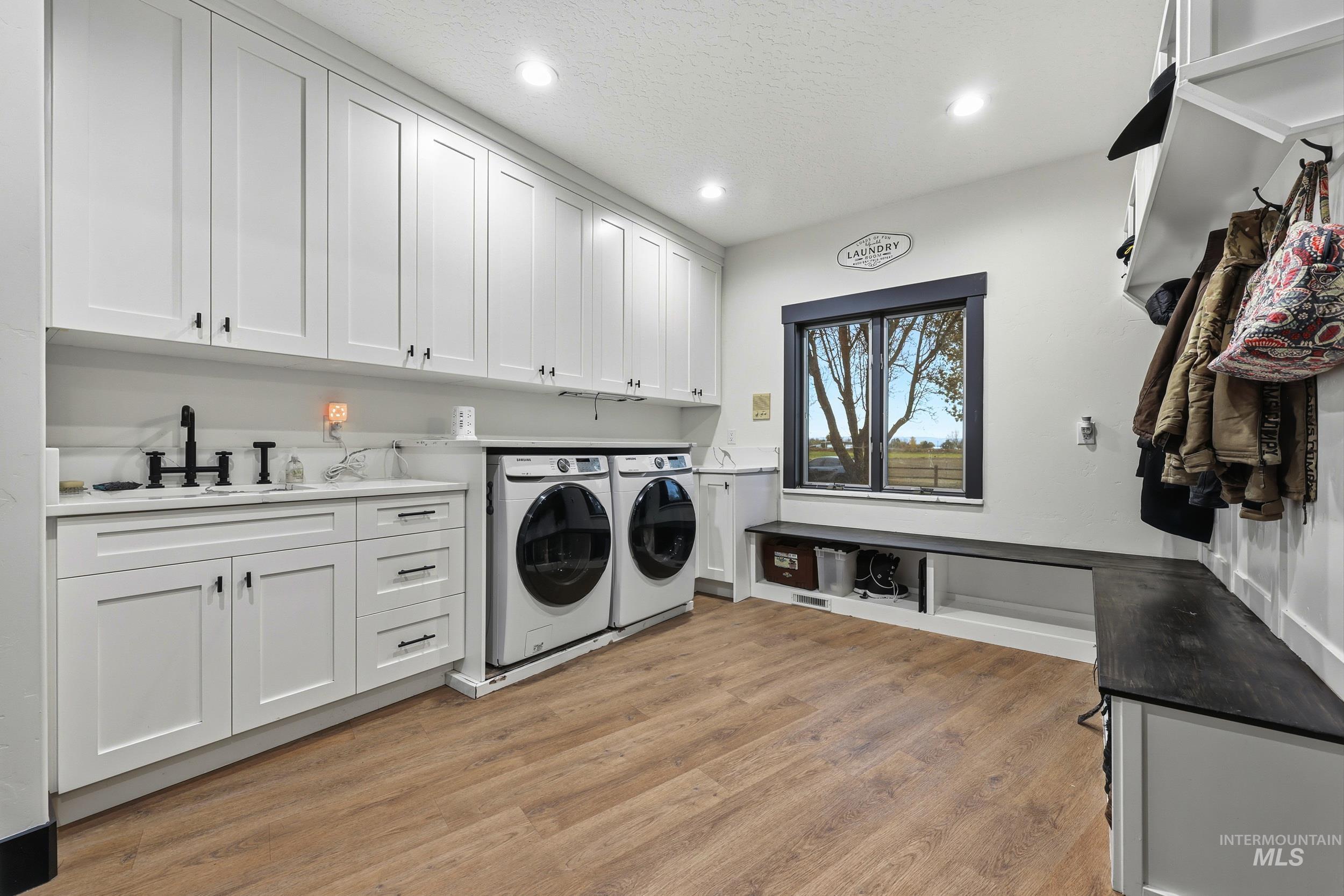 25300 Harvey Road Caldwell, ID 83607 - Photo 21 of 50 Washroom with cabinet space, light wood finished floors, washer and dryer, recessed lighting, and a textured ceiling