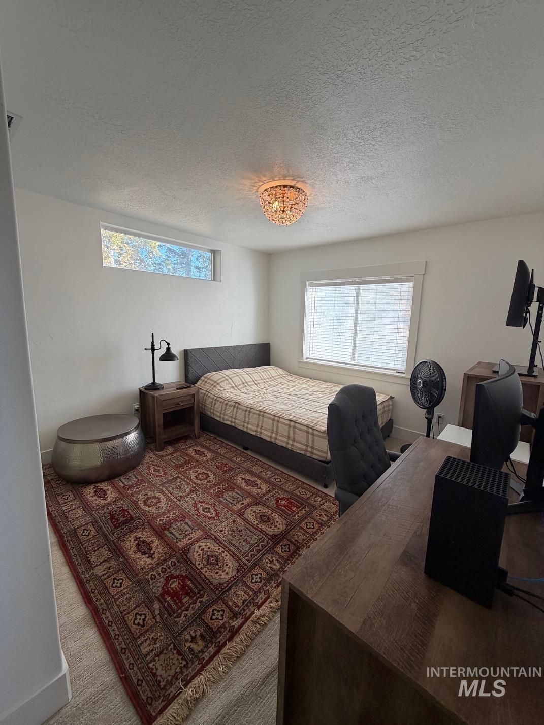 25300 Harvey Road Caldwell, ID 83607 - Photo 29 of 50 Bedroom featuring multiple windows, a textured ceiling, carpet floors, and a desk