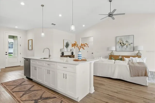 a large white kitchen with a stove a sink a window and wooden floor