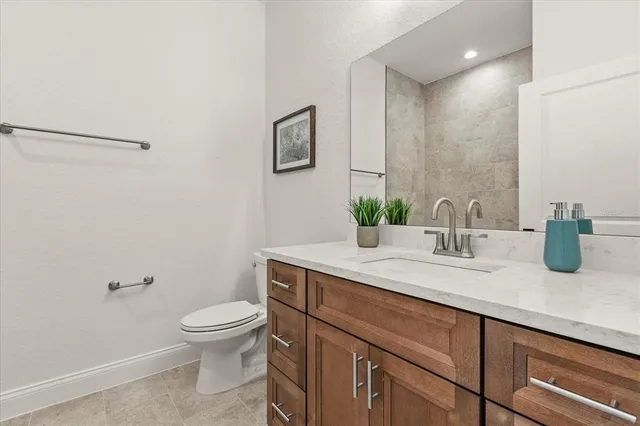 a bathroom with a granite countertop sink a toilet and a mirror