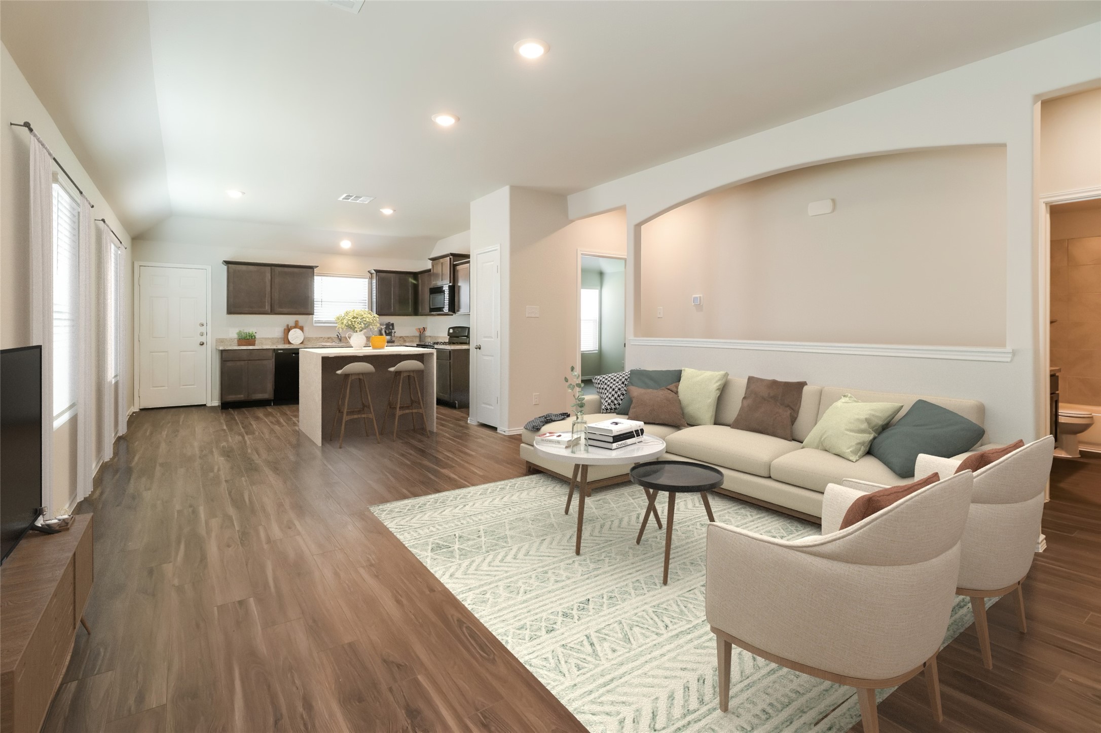 a living room with furniture wooden floor and a kitchen view