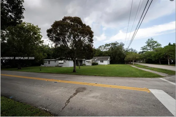a view of a house with a big yard and large trees