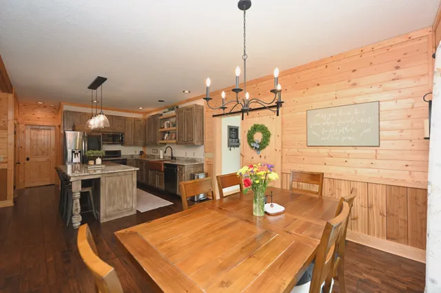 a open kitchen with stainless steel appliances kitchen island granite countertop a stove a sink a dining table and chairs with wooden floor