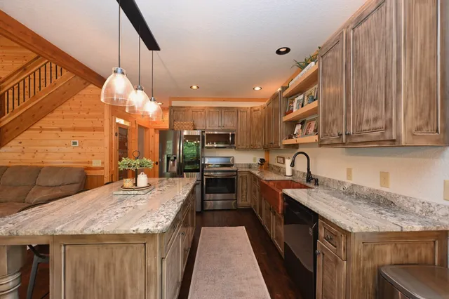 a kitchen with stainless steel appliances granite countertop a sink a stove and a wooden cabinets
