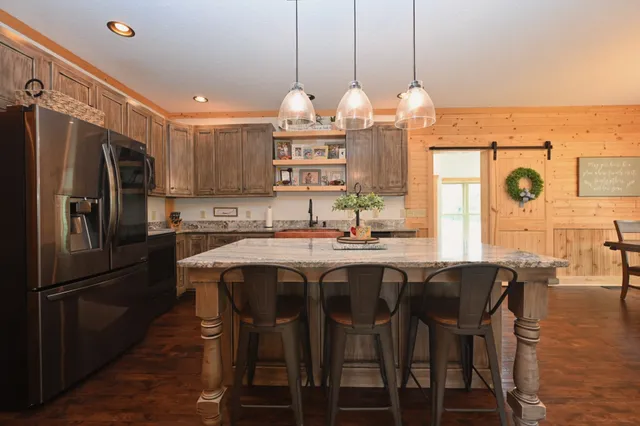 a kitchen with stainless steel appliances a dining table chairs stove and refrigerator
