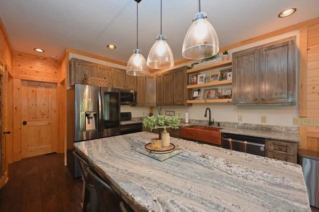 a kitchen with stainless steel appliances kitchen island granite countertop a refrigerator a stove and a wooden floors