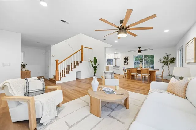 a living room with furniture white walls and a dining table with wooden floor