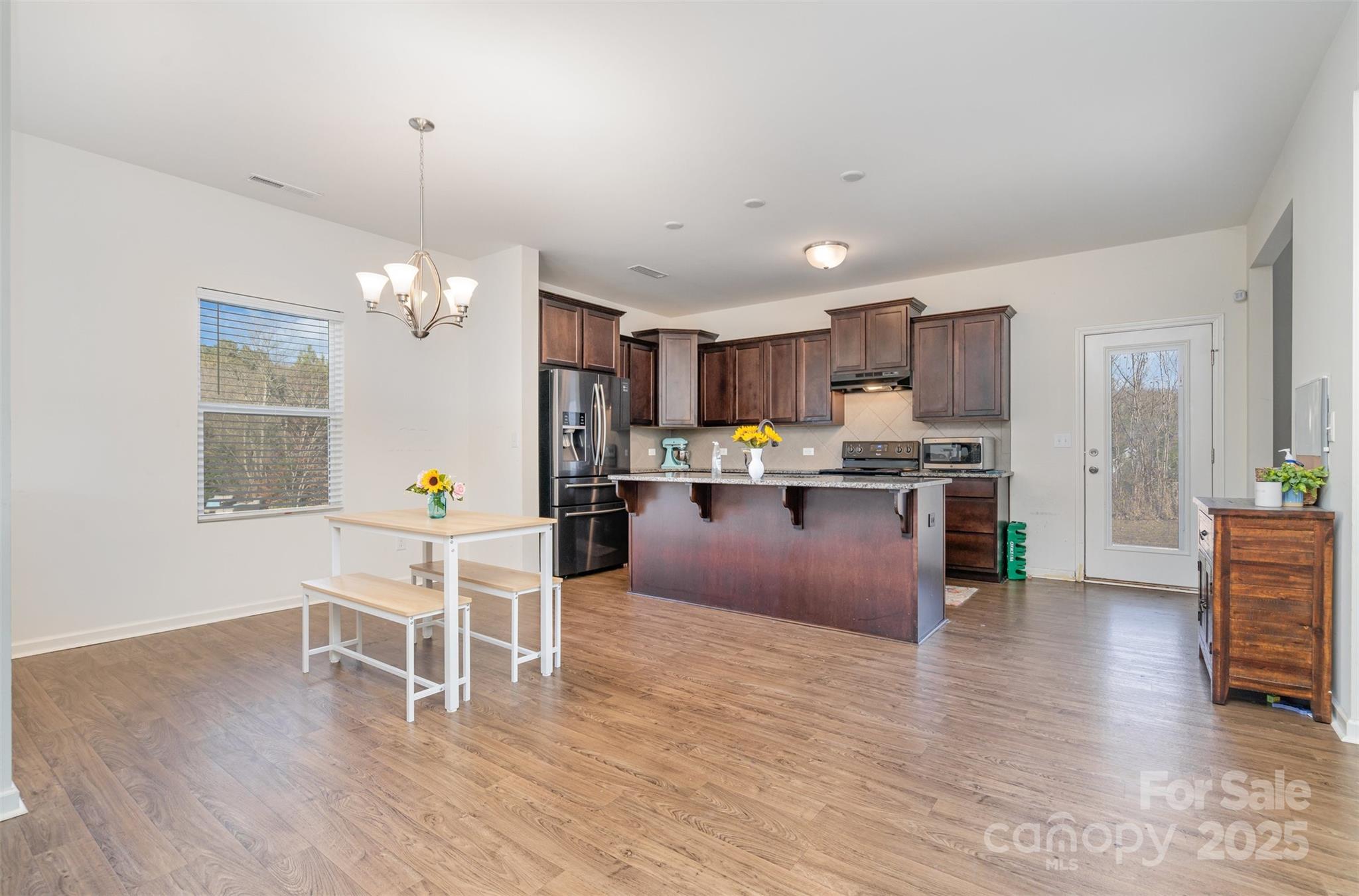 8009 Camden Crossing Lowell, NC 28098 - Photo 7 of 20 a kitchen with stainless steel appliances kitchen island granite countertop wooden floors and cabinets