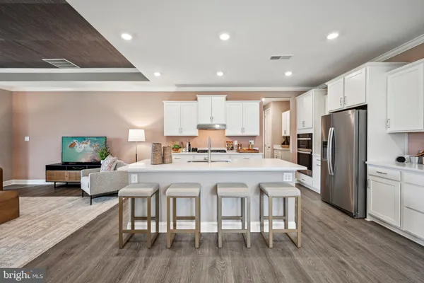 a kitchen with stainless steel appliances granite countertop a refrigerator a stove a sink a dining table and chairs with wooden floor
