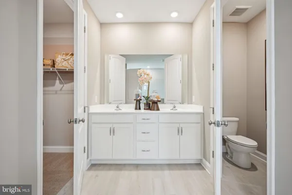 a spacious bathroom with a vanity a toilet a sink and a mirror