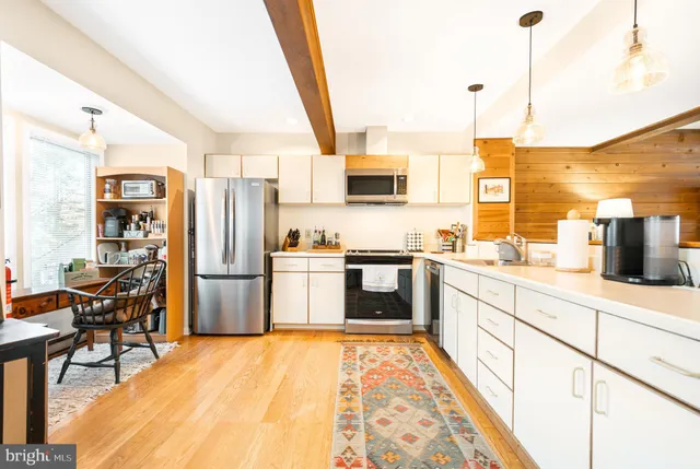 a kitchen with stainless steel appliances kitchen island granite countertop a table chairs and a refrigerator