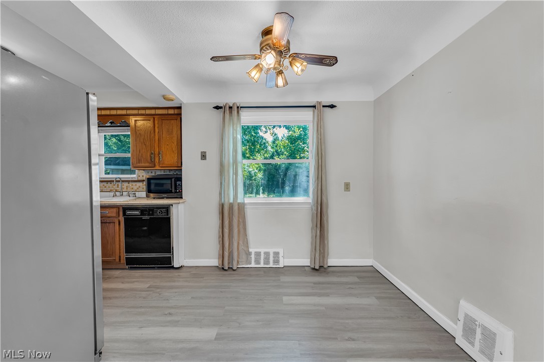 3842 Wallingford Road South Euclid, OH 44121 - Photo 11 of 31 Kitchen featuring appliances with stainless steel finishes, ceiling fan, light hardwood / wood-style flooring, and tasteful backsplash
