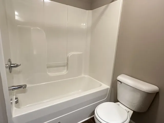 a white toilet sitting next to a bath tub