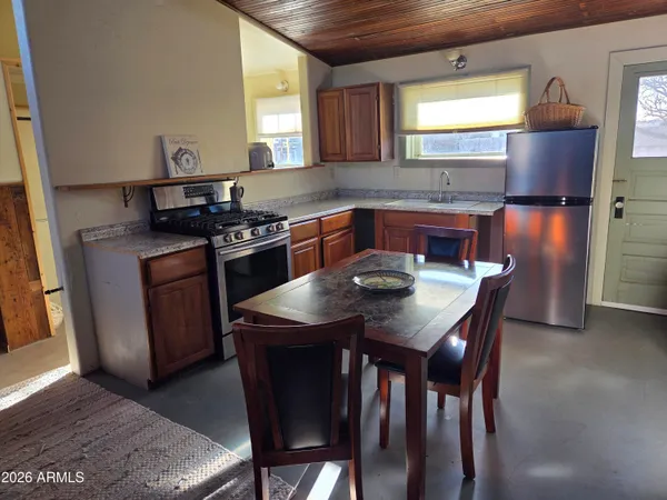 a kitchen with stainless steel appliances granite countertop a stove a refrigerator a sink a dining table and chairs
