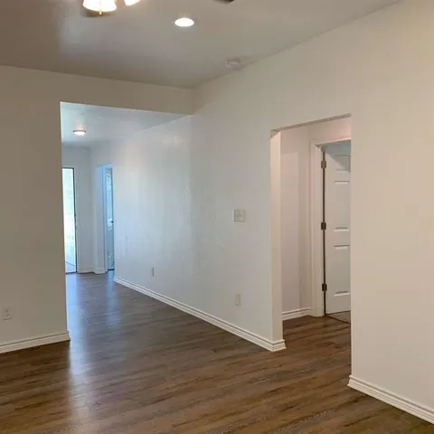 a view of an empty room with wooden floor and closet