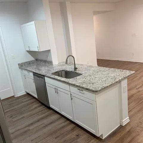 a utility room with granite countertop cabinets and sink