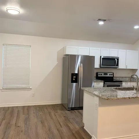 a kitchen with granite countertop a refrigerator and a stove top oven