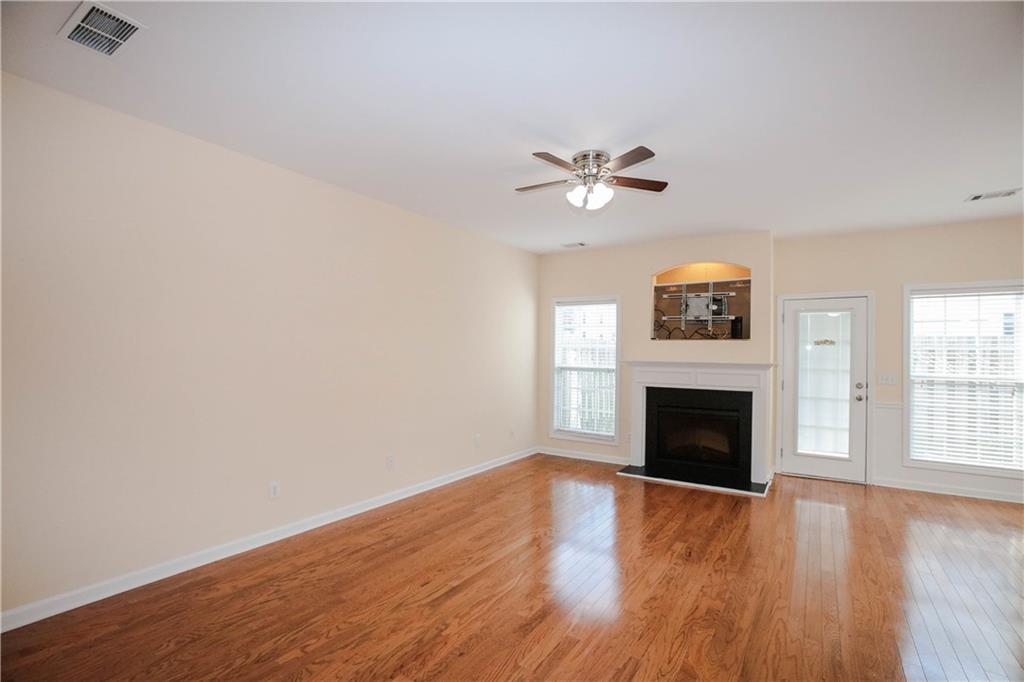 3801 Thayer Trace Duluth, GA 30096 - Photo 12 of 44 an empty room with windows fireplace and a ceiling fan