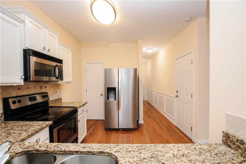 3801 Thayer Trace Duluth, GA 30096 - Photo 19 of 44 a kitchen with stainless steel appliances granite countertop a refrigerator a stove and a sink with wooden floor