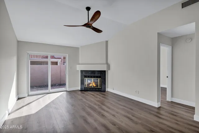 a view of an empty room with wooden floor fireplace and a window