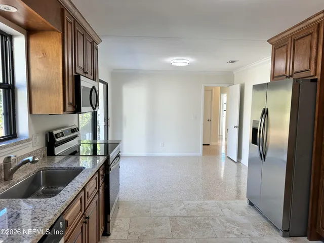a kitchen with stainless steel appliances granite countertop a refrigerator a stove and a sink with wooden floor