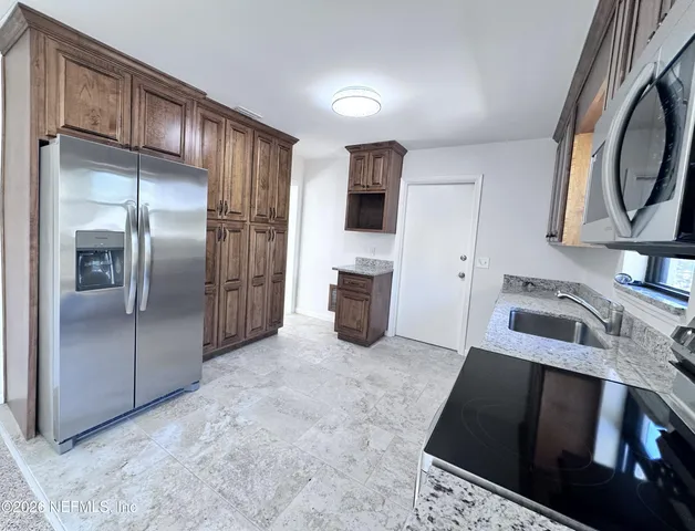 a kitchen with stainless steel appliances granite countertop a stove refrigerator and a microwave