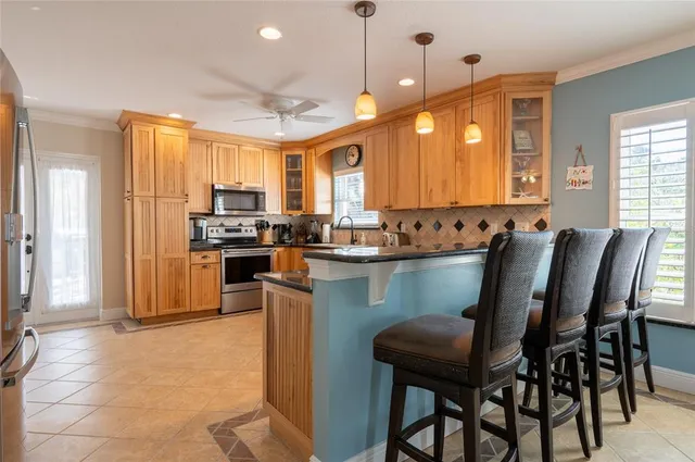 a kitchen with stainless steel appliances granite countertop a table chairs sink refrigerator and microwave