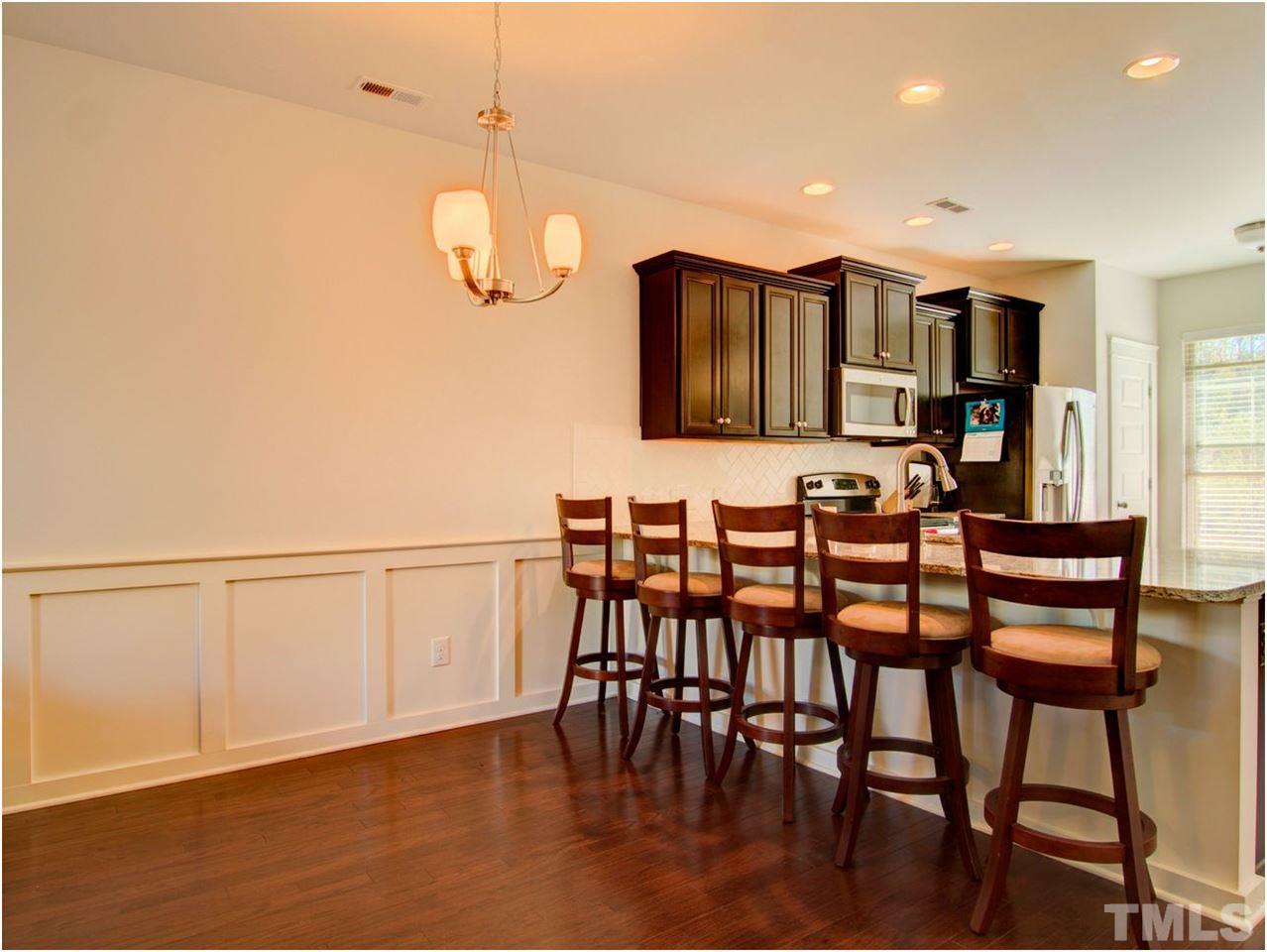 7902 Allscott Way Raleigh, NC 27612 - Photo 5 of 25 Sleek craftsman woodwork in the dining area to define a dining space, but if you don't have or want a table, look at all the chairs the bar can fit!