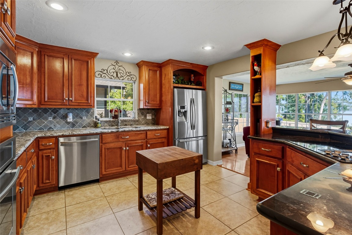 200 Trott Lane Point Blank, TX 77364 - Photo 13 of 50 a kitchen with stainless steel appliances granite countertop a refrigerator a sink dishwasher a stove and a dining table with wooden cabinet