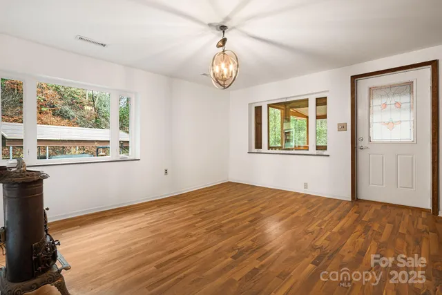 a view of an empty room with window and wooden floor