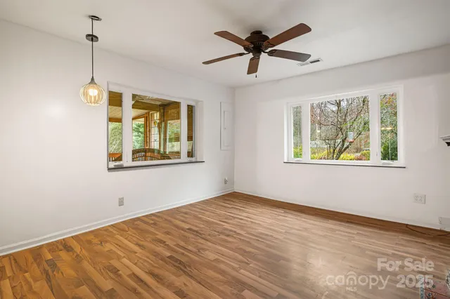 a view of empty room with wooden floor and window