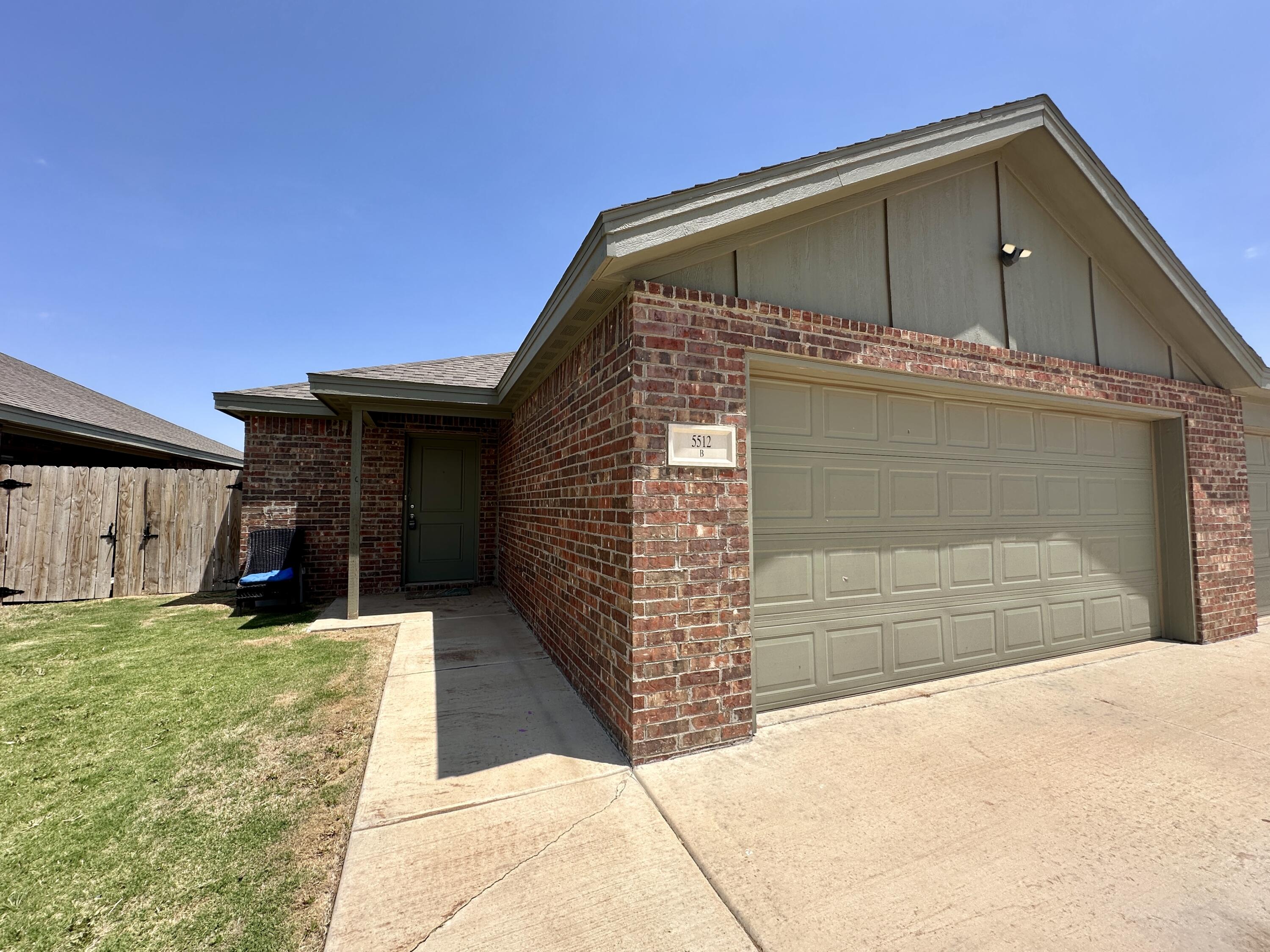 5512 122nd Street, Unit B Lubbock, TX 79424 - Photo 1 of 9 a front view of a house with a yard and garage