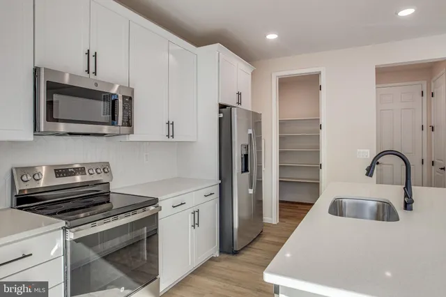 a kitchen with stainless steel appliances a stove microwave and a sink