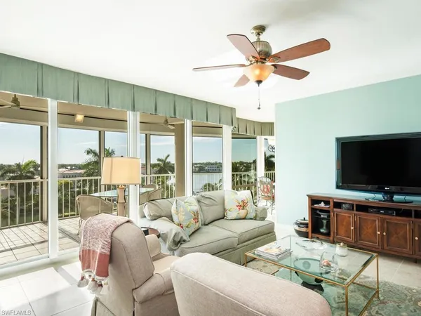 a living room with furniture a flat screen tv and a large window