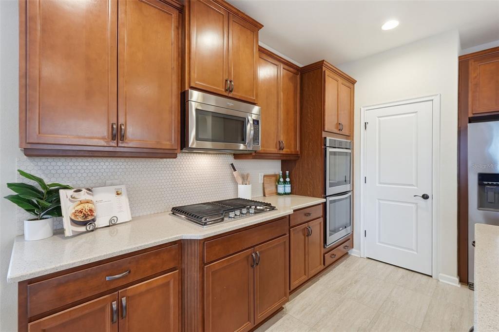 29241 Perilli Place Wesley Chapel, FL 33543 - Photo 12 of 53 a kitchen with stainless steel appliances granite countertop a refrigerator a stove and a sink with wooden floor