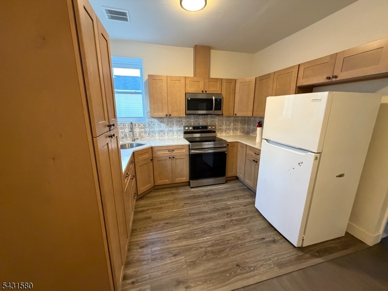 a kitchen with a refrigerator sink stove and wooden floor