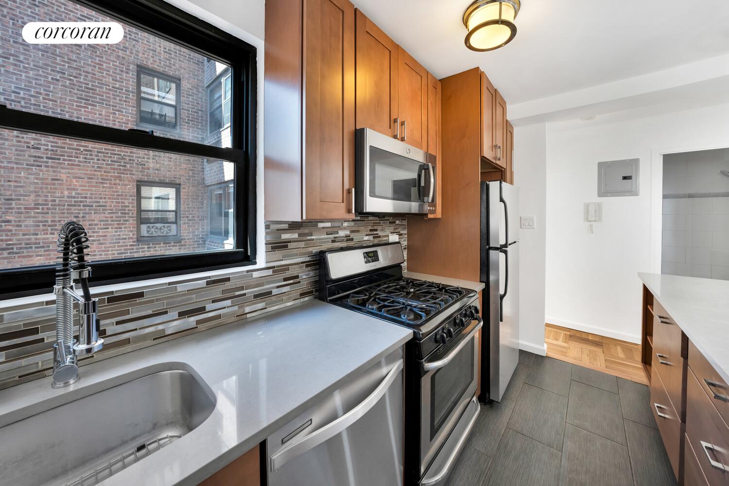 233 East 69th Street, Unit 12K Manhattan, NY 10021 - Photo 8 of 10 a kitchen with stainless steel appliances a sink stove and microwave