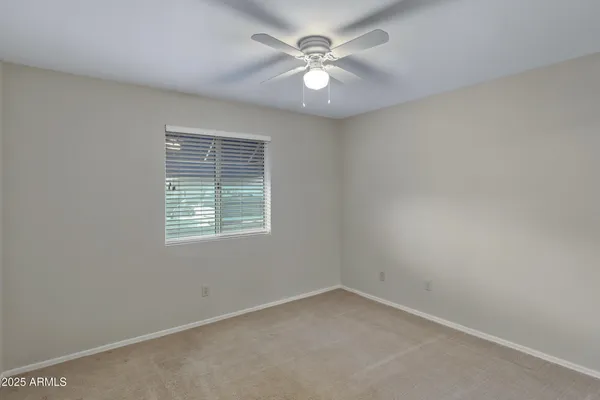 an empty room with a window and a fan