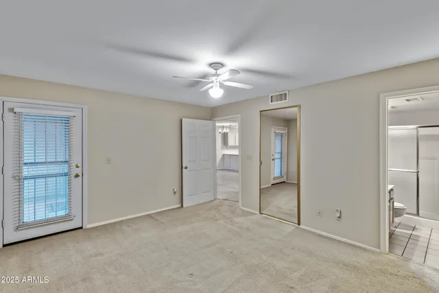 an empty room with closet and a ceiling fan
