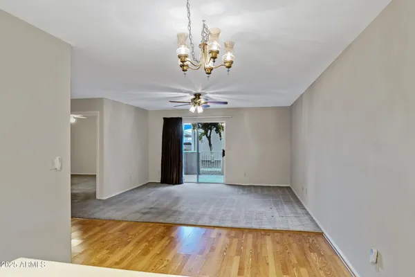 a view of a livingroom with a chandelier fan and kitchen view