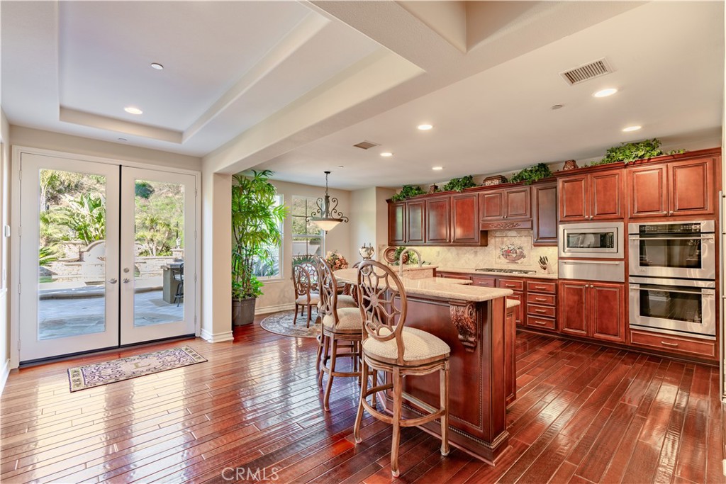 4023 Elderberry Circle Corona, CA 92882 - Photo 15 of 74 a kitchen with stainless steel appliances kitchen island granite countertop wooden floors and wooden cabinets