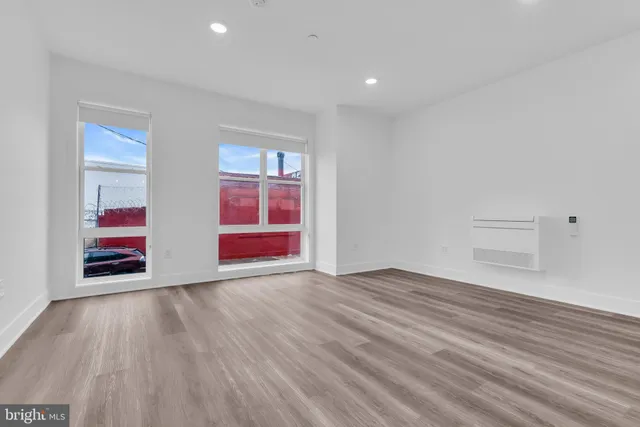 a view of an empty room with wooden floor and windows