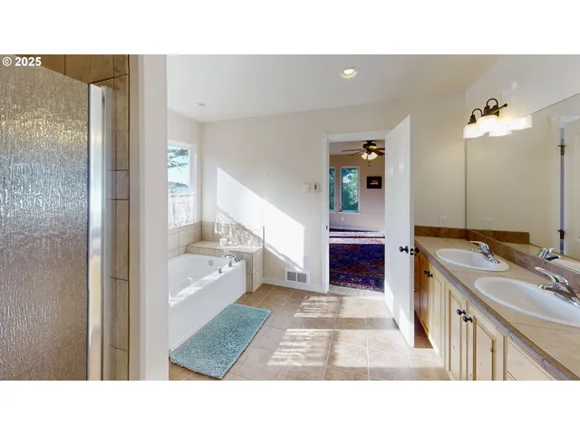 a bathroom with a tub sink vanity granite and a shower