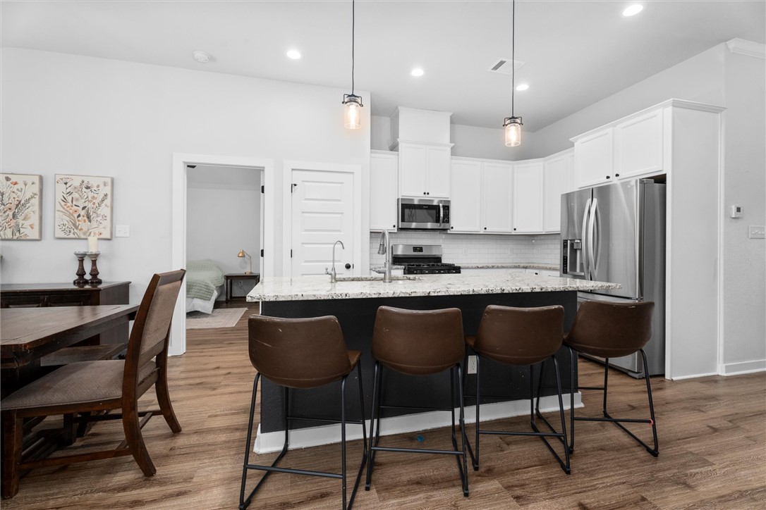 3027 Wolfpack Loop Bryan, TX 77808 - Photo 15 of 39 a kitchen with stainless steel appliances kitchen island granite countertop a table chairs microwave and sink
