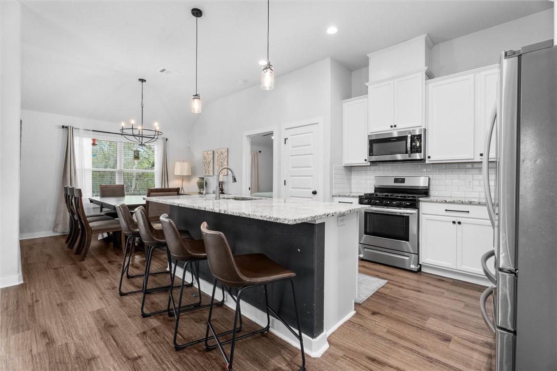 3027 Wolfpack Loop Bryan, TX 77808 - Photo 16 of 39 a kitchen with kitchen island granite countertop a sink cabinets and stainless steel appliances