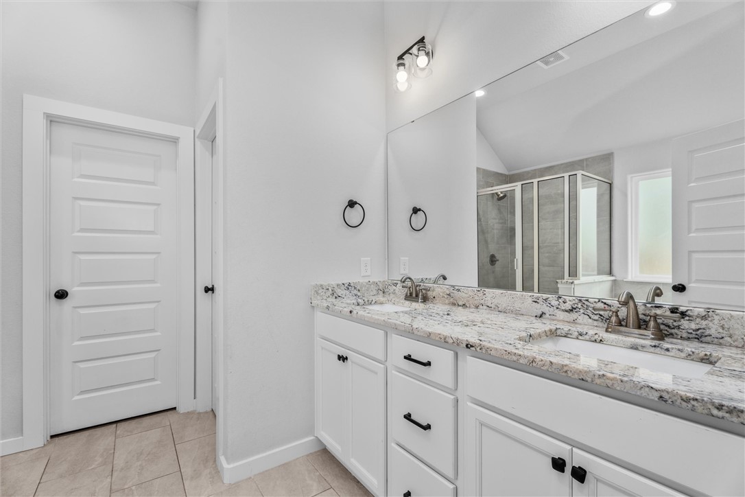 3027 Wolfpack Loop Bryan, TX 77808 - Photo 24 of 39 a bathroom with a granite countertop sink and a mirror