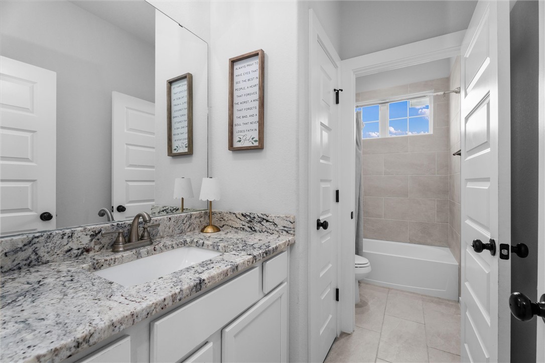 3027 Wolfpack Loop Bryan, TX 77808 - Photo 29 of 39 a bathroom with a granite countertop sink a toilet and shower