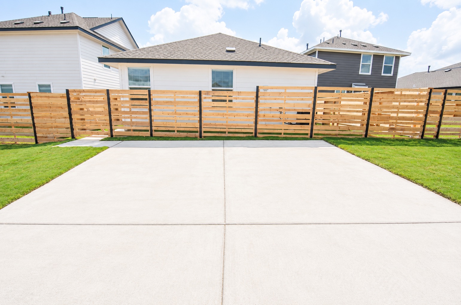 397 Keefer Kyle, TX 78640 - Photo 32 of 33 A fresh concrete driveway offers ample parking and leads to a newly fenced backyard with vibrant green grass.